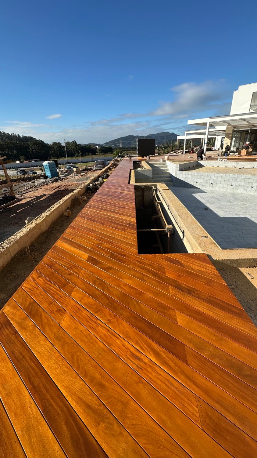 Deck da Casa Pirão já pintado, correndo ao longo da piscina com a casa e as montanhas ao fundo