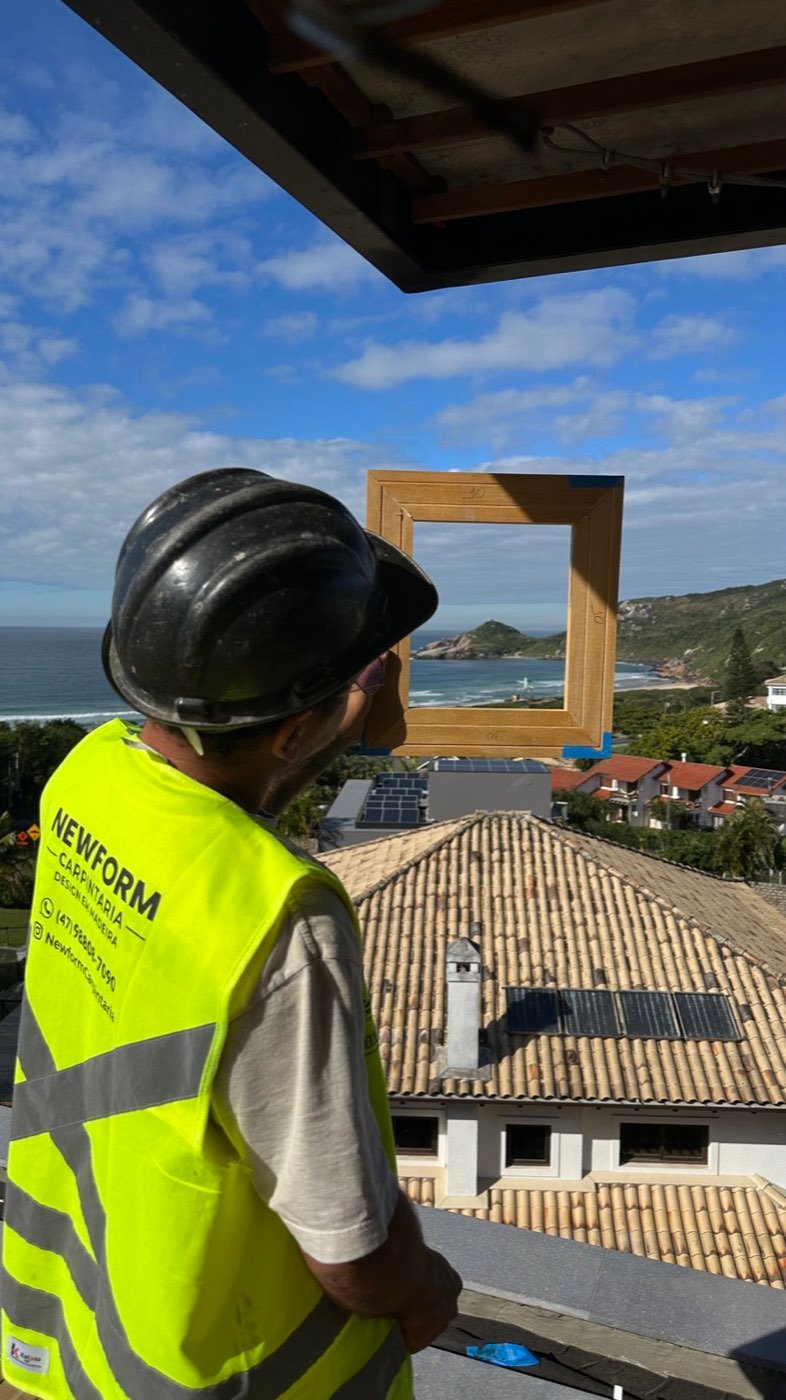 Colaborador da New Form diante da moldura de madeira que emoldura a vista para o mar