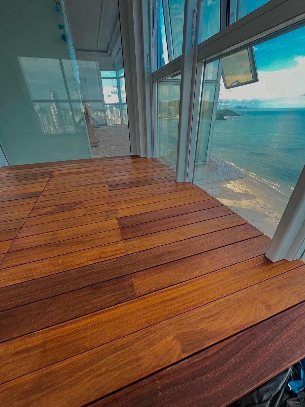Deck de madeira recém-envernizado em apartamento de frente para o mar