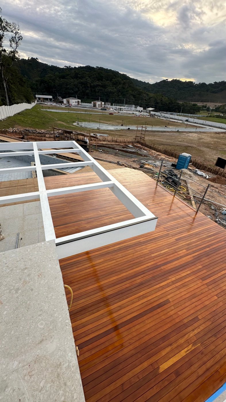 Deck de madeira nobre visto do pavimento superior, contornando a área da piscina